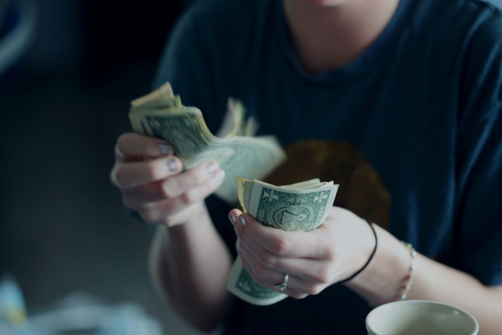 focus photography of person counting dollar banknotes focus photography of person counting dollar banknotes